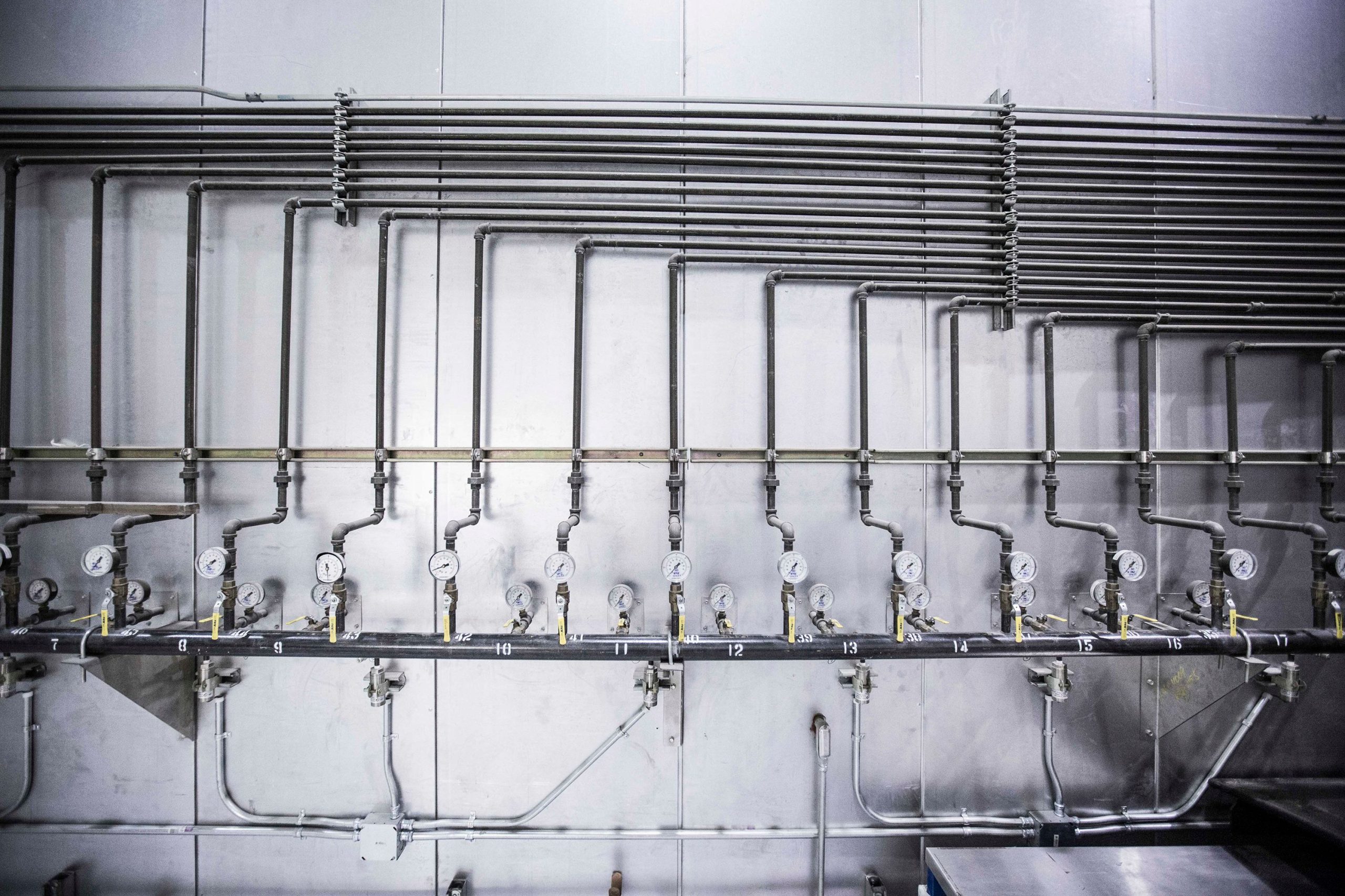 Row of industrial pressure gauges and steel manifold piping in an ASEAN processing plant, representing supply chain risk stress-testing and origin verification for EU importers.