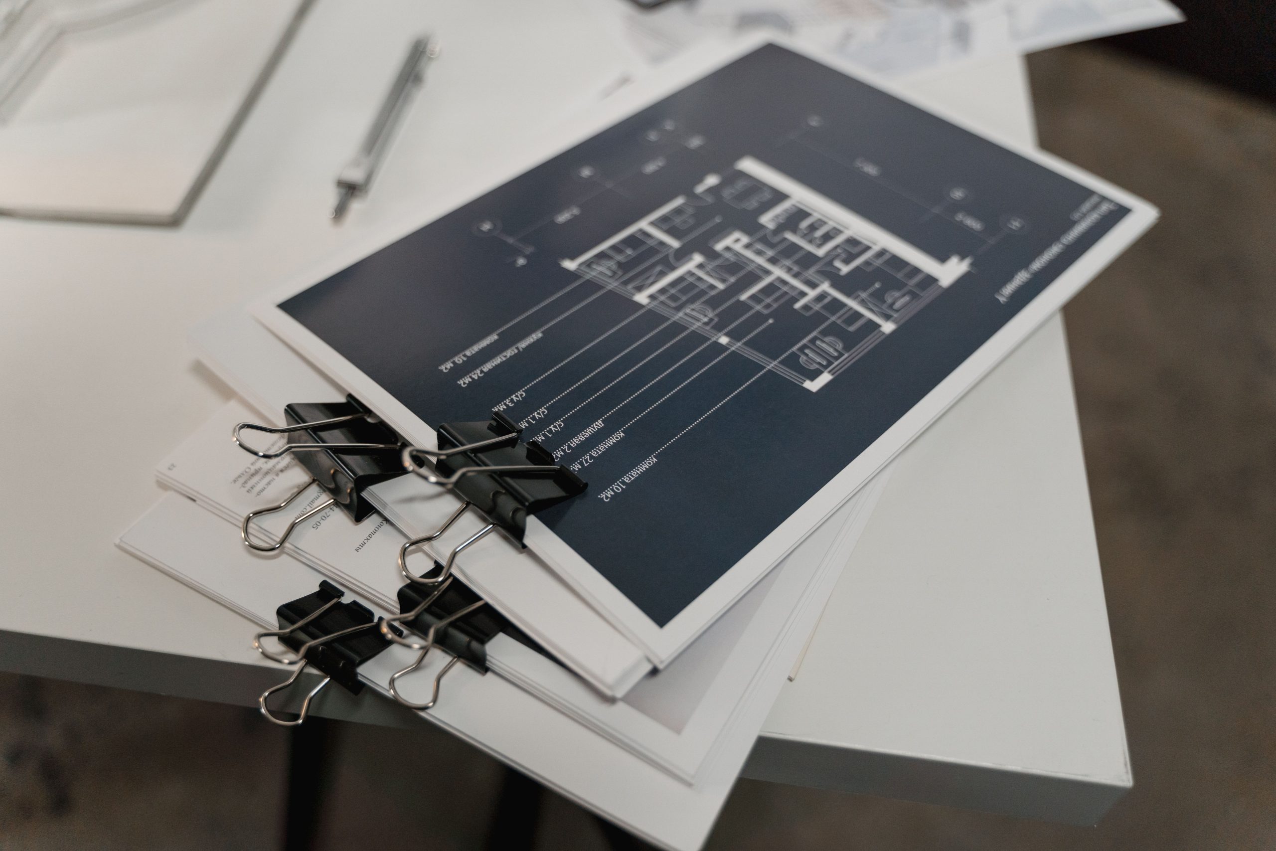 Stacked technical blueprints and audit documentation secured with binder clips representing forensic supply chain verification standards