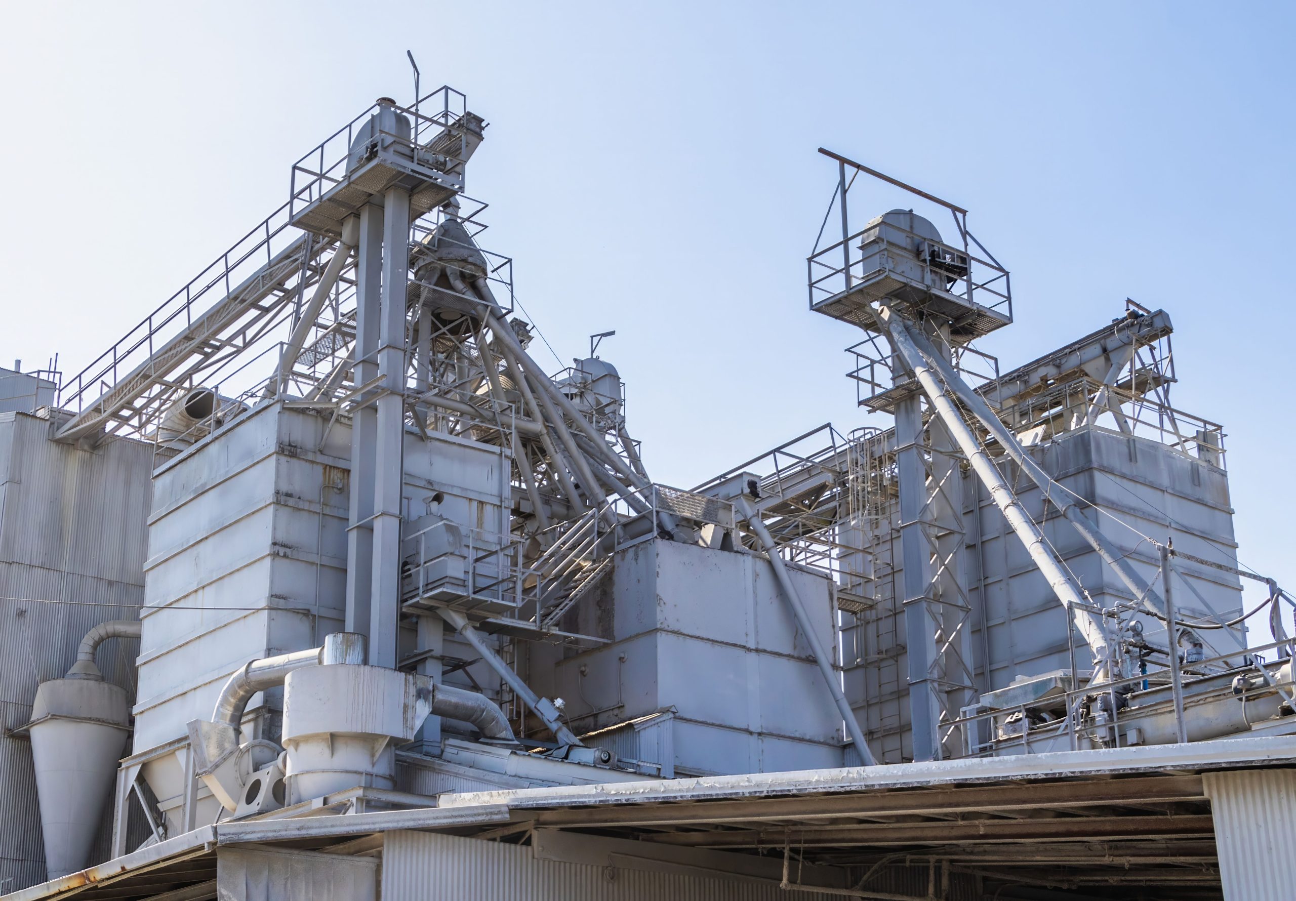 Dry-bulk material processing plant with corrugated steel silos and bucket elevators undergoing forensic verification for ASEAN supply chains